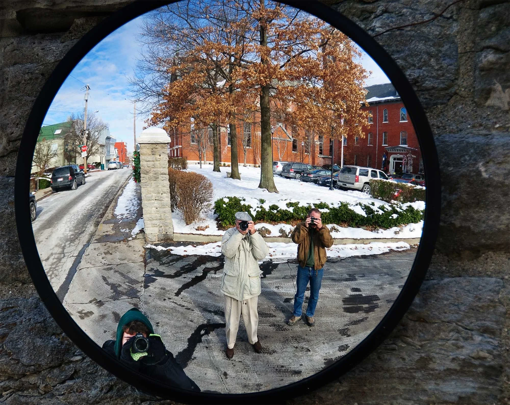Two photographers shooting outdoors in winter, viewed through a circular stone opening — personal photography story by Deborah Heinlen Photography
