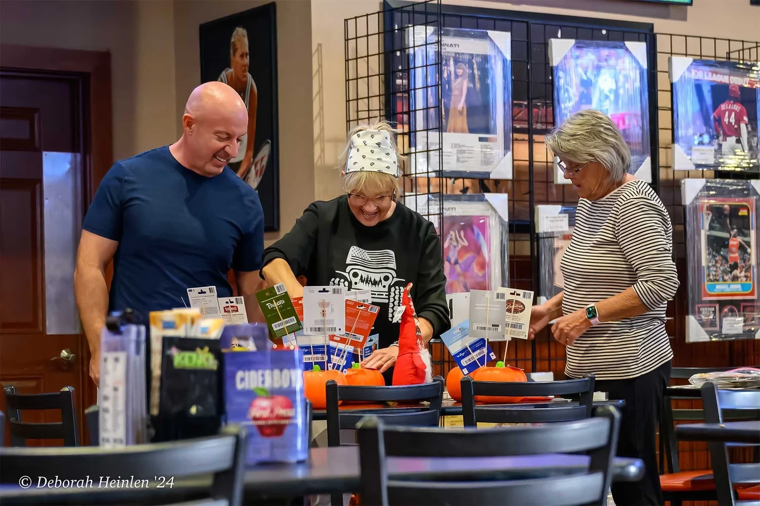 Corporate event candid photography by Deborah Heinlen Photography, Cincinnati — three people laughing while setting up a charity auction prize table