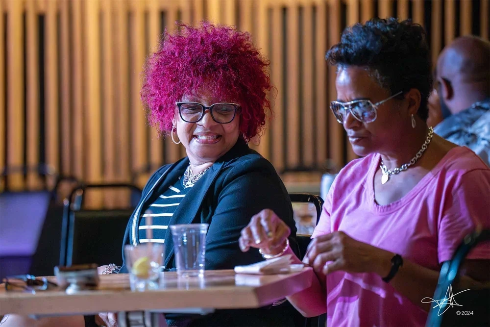 Corporate event candid photography by Deborah Heinlen Photography, Cincinnati — two women sharing a laugh at a table during a corporate networking event