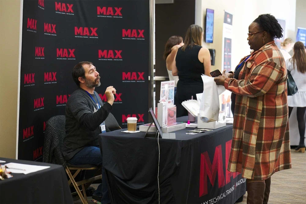 Corporate event photography by Deborah Heinlen Photography, Cincinnati — two professionals at a MAX branded vendor booth at a business conference