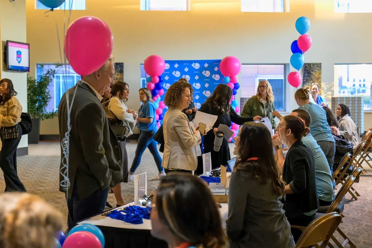 Corporate event photography by Deborah Heinlen Photography, Cincinnati — conference attendees mingling with pink and blue balloon decor at a business event