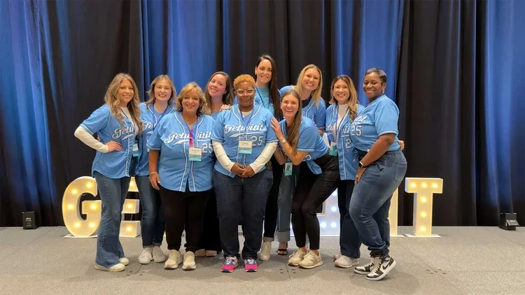 Corporate event group photo by Deborah Heinlen Photography, Cincinnati — team of women in matching blue jerseys posing together at a corporate event