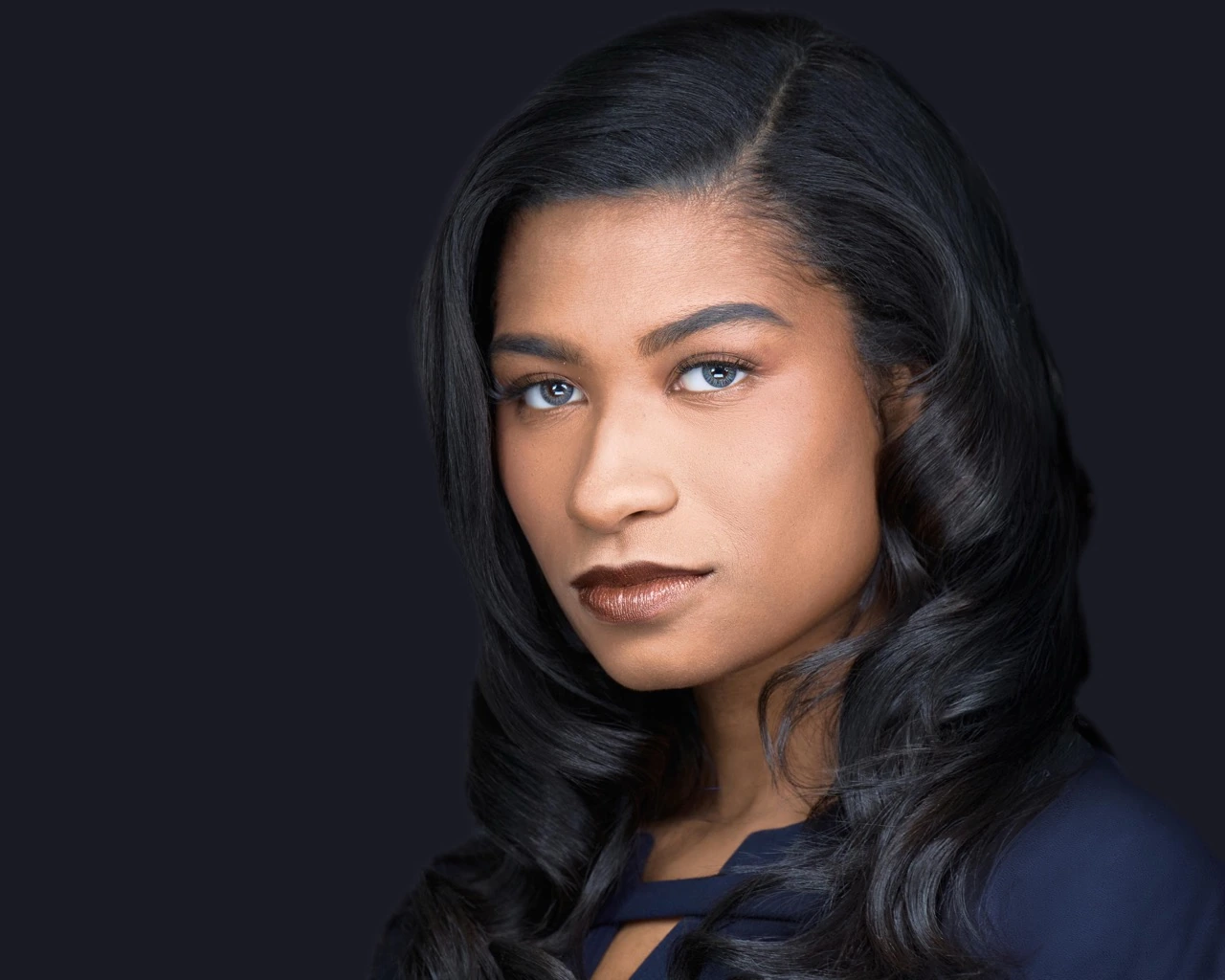 Professional female headshot by Deborah Heinlen Photography, Cincinnati — smiling woman with dark hair and bangs against dark studio background