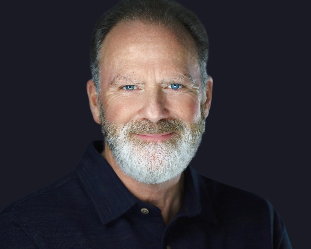 Professional male headshot by Deborah Heinlen Photography, Cincinnati — distinguished man with white beard in dark shirt against dark studio background