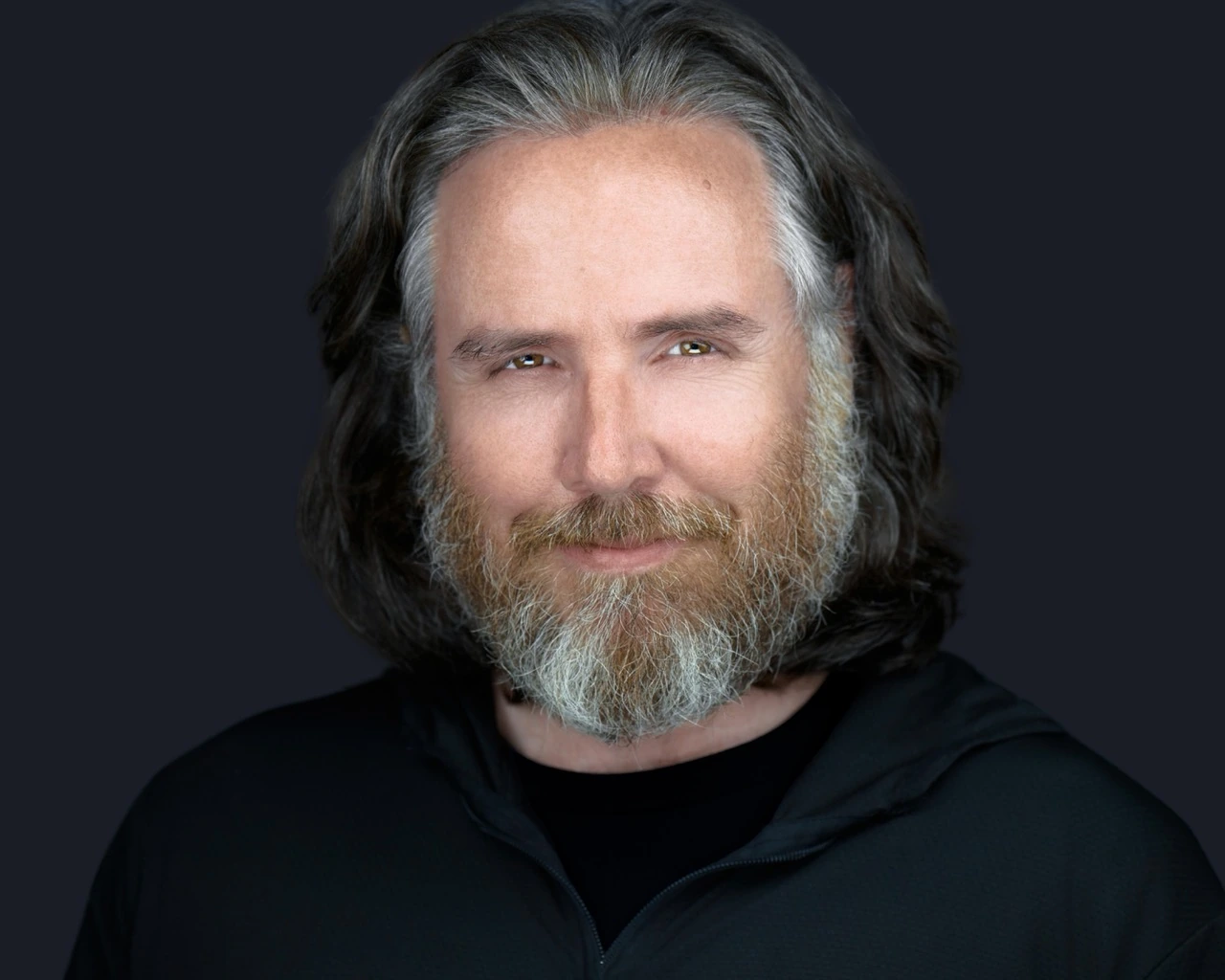 Professional male headshot by Deborah Heinlen Photography, Cincinnati — distinguished man with gray beard in dark shirt against dark studio background