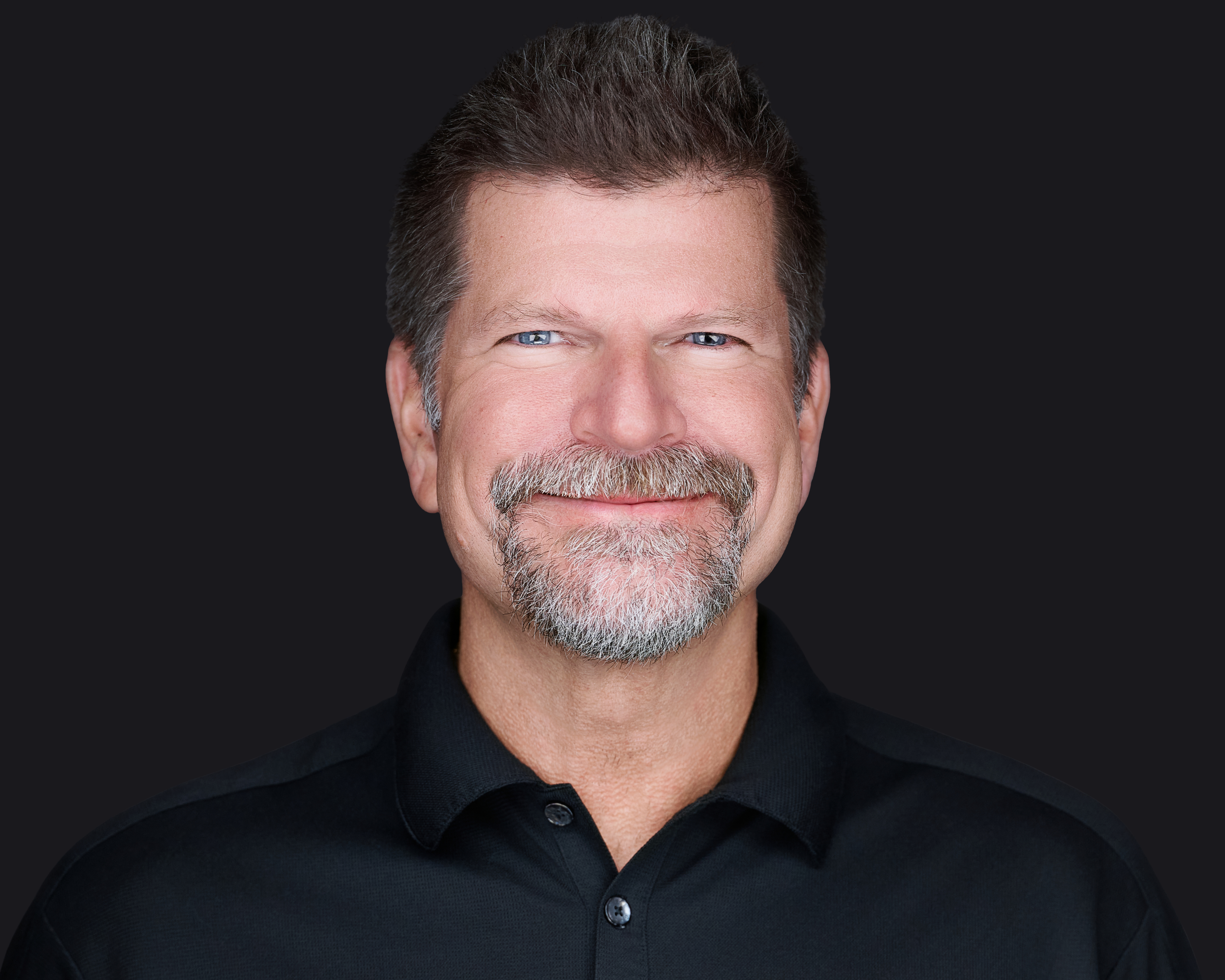 Professional male headshot by Deborah Heinlen Photography, Cincinnati — man in gray blazer and patterned shirt against dark background