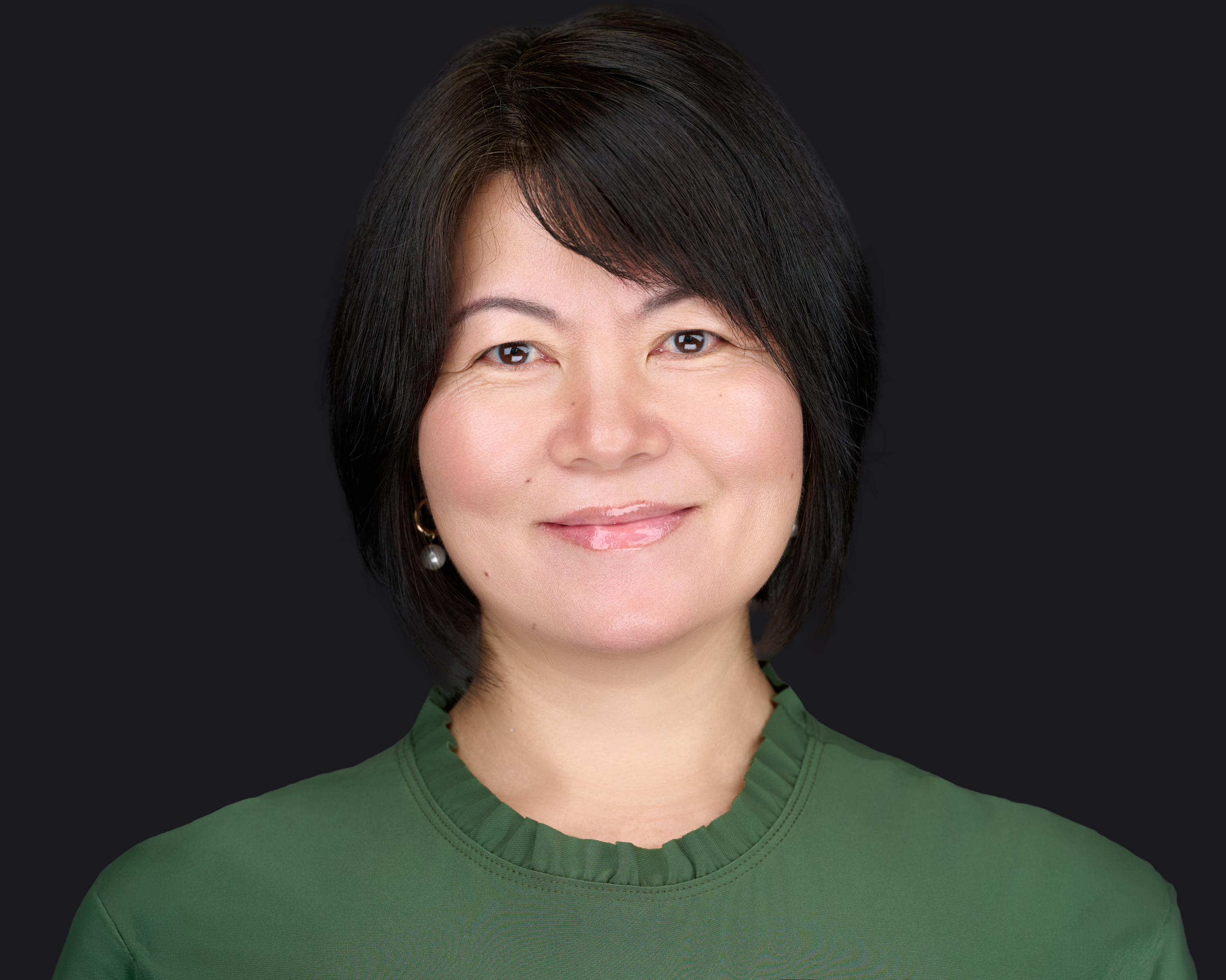 Professional female headshot by Deborah Heinlen Photography, Cincinnati, smiling woman with black hair in green top against dark studio background